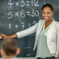 A female math teacher demonstrating at the chalkboard