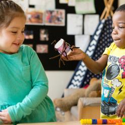 Preschool boy showing girl his craft project