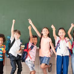 Diverse young students cheering at blackboard