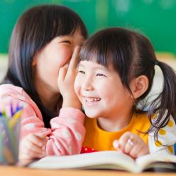Two girls whispering and smiling