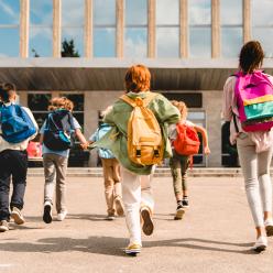 Kids with backpacks running to school building