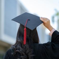 A person in a graduation cap and gown from behind