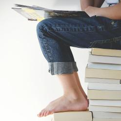 The legs of a child who is sitting on a stack of books