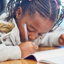 Young girl with braids writing intently