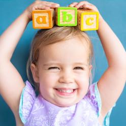 Smiling child holding letter blocks on their head
