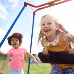 Two children smiling on the swings