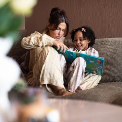 Parent reading to a child on the couch.