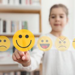 A child selecting a smiling emoji from a line of emojis.