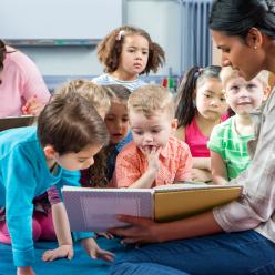 Teacher reading aloud to a group of young children.