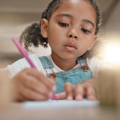 A girl writing on a worksheet.