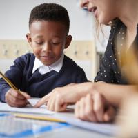 Teacher helping boy with his writing