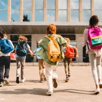 Kids with backpacks running to school building