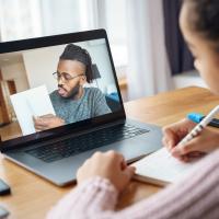 Man on the computer helping a young student with her school work.