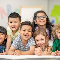 A group of diverse elementary age students smiling at camera