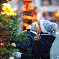 Two kids looking at a tree in the snow