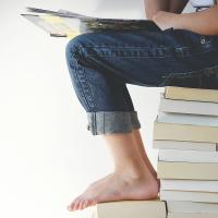 The legs of a child who is sitting on a stack of books