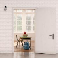 An open doorway to a classroom with a single desk, backpack, and books