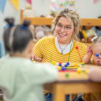 Smiling teacher working with young students.