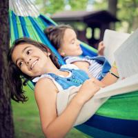 Two young children reading in a hammock.